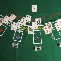 Stół do gry w blackjacka, karty i żetony. Widać karty z królem, damą i asem. Gra 21 w toku.