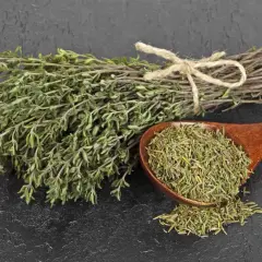 Manojo de tomillo fresco y seco en cuchara de madera. El tomillo para que sirve es para dar sabor a comidas y como remedio natural.