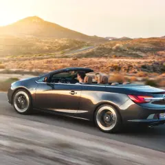 Para podróżuje kabrioletem Opel Cascada przez pustynny krajobraz o zachodzie słońca.