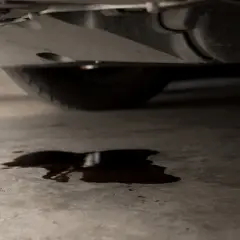 Mancha de aceite en el suelo bajo un coche. ¿Cuánto costará arreglar mi coche si pierde aceite?