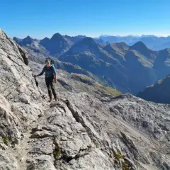 Wanderer auf dem Heilbronner Weg, gesichert an einem Stahlseil, genießt die atemberaubende Bergkulisse.