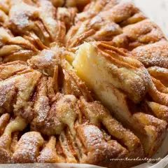 Una deliziosa torta di mele, cosparsa di zucchero a velo, con una fetta sollevata che rivela la morbida consistenza.