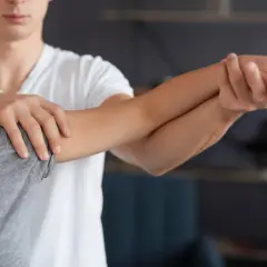 Fizjoterapeuta pomaga pacjentce, która nie może wyprostować ręki w łokciu.