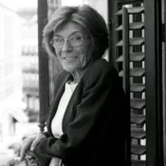 Carmen Rico Godoy, con gafas y chaqueta, mira a la cámara desde un balcón. Parece una escena de "Carmen Rico Godoy abandonada".