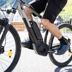 Rower elektryczny z baterią w ramie i silnikiem w korbie. Widoczna noga rowerzysty na pedale, pokazująca, jak działa rower elektryczny, wspomagając jazdę.