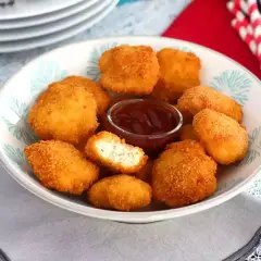 En skål med gyllene chicken nuggets och en liten skål med ketchup. Perfekt för en snabb och god måltid.