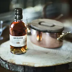 Bouteille d'Aberlour 18 ans, un whisky d'exception, posée sur une tranche de bois. Une expérience de dégustation unique, fruit d'une **création whisky** raffinée.