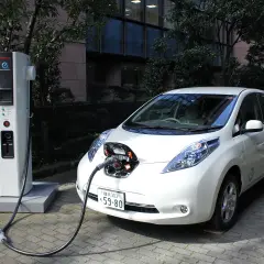 Biały Nissan Leaf podłączony do ładowarki. To przyszłość, czyli serwis samochodów elektrycznych.