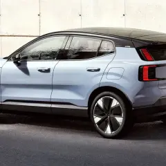 Nowy, elektryczny Volvo EX30 w kolorze jasnoniebieskim prezentuje się nowocześnie na tle betonowej ściany.