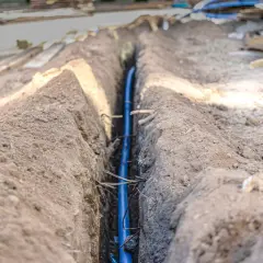 Wykopany rów z niebieską rurą, prawdopodobnie na jakiej głębokości kabel elektryczny zostanie ułożony.