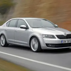 Srebrna Octavia III pędzi po drodze, koła rozmyte od prędkości.