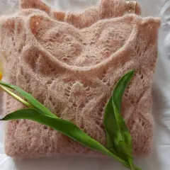 Delikatny, różowy sweterek z ażurowym wzorem, obok żółty tulipan. Idealny przykład, jak zrobić sweter na drutach krok po kroku.