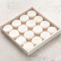 Un plateau en bois présente une rangée de petits fromages ronds, évoquant l'origine du saint marcellin fromage.