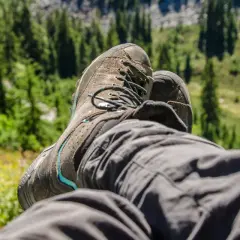 A hiker rests, their well-worn boots laced snugly. This image shows how hiking boots fit, offering comfort and support on the trail.