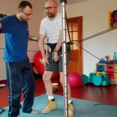 Fizjoterapeuta pomaga pacjentowi ćwiczyć z użyciem sprzętu do rehabilitacji po udarze mózgu.