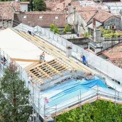 Pracownicy realizują projektowanie dachu, montując drewnianą konstrukcję na budynku.
