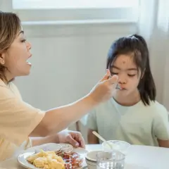 Matka karmi łyżeczką niepełnosprawne dziecko. Troska o przyszłość, wsparcie w codzienności, jak renta rodzinna dla niepełnosprawnego dorosłego dziecka.