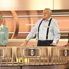 Trzech uczestników programu "Koło Fortuny" - Marianna, Władysław i Anna - stoi przy swoich stanowiskach.