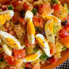 Ensalada campera con patatas, huevos duros, tomate, pimiento y aceitunas. Ingredientes frescos y sabrosos.