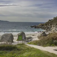 La playa de ancoradouro, con su arena blanca, rocas imponentes y el mar azul, invita a la contemplación. Un sendero de piedra serpentea hacia la costa.
