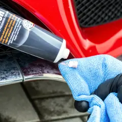 Krem do polerowania Metal Polish nałożony na niebieską mikrofibrę, gotowy do czyszczenia chromowanych listew w aucie.