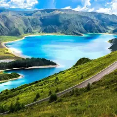 Carretera serpenteante en una ladera verde con lagos azules y montañas al fondo, un paisaje idílico de Portugal en octubre.