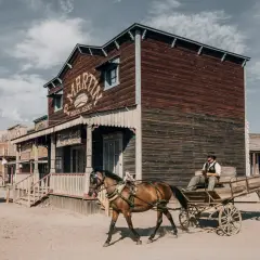 Un vaquero conduce un carro tirado por caballos por un pueblo del Salvaje Oeste en el desierto de Tabernas y Oasys Minihollywood.