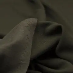 Miękki, ciemnozielony trykot, co to za materiał? Idealny na wygodne ubrania, z delikatnymi dziurkami przy krawędzi.