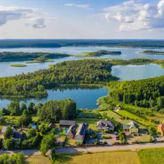 Malownicze jezioro Charzykowskie z licznymi zatoczkami i wyspami, otoczone lasami. Na brzegu widać domy i pola.