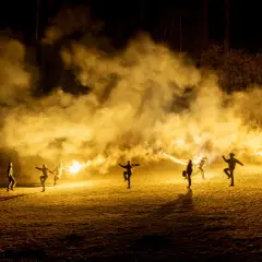 Silvia Gallerano e un gruppo di persone danzano tra fumo e bengala, creando un'atmosfera magica e un po' caotica, quasi come se stessero scacciando "la merda" della vita.