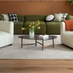Ein grünes Sofa mit Kissen, die das Sofa dekorieren und richtig kombinieren. Zwei weiße Sessel und ein Couchtisch mit Blumen.