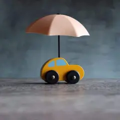 Voiture jaune sous parapluie, symbolisant une assurance courte durée.