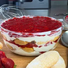 Un invitante tiramisù alle fragole in una ciotola di vetro, con savoiardi, crema e fragole fresche.
