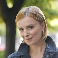 Portret Haliny Młynkowej z krótkimi blond włosami, w kurtce, na tle drzew.
