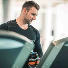 Mężczyzna z odżywką Supernova na bieżni, zastanawia się, czy robić cardio na masie.