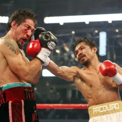 Intensiv boxning match där en boxare träffas hårt i ansiktet. Blod stänker och motståndaren levererar en kraftfull slag.
