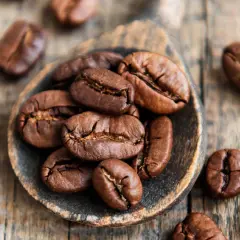 Chicchi di caffè tostati su un cucchiaio di legno, simbolo di alta qualità di caffè.