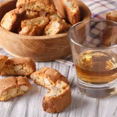 Kieliszek wina Vin Santo i cantucci z migdałami na drewnianym stole.