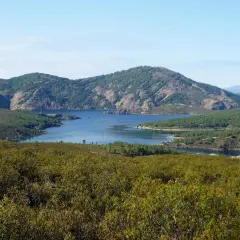Paisaje sereno con un embalse azul rodeado de montañas verdes. La senda del Genaro se adentra en este idílico entorno natural.