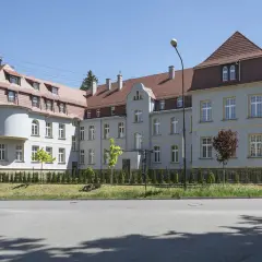 Elegancki budynek z wieżyczką, gdzie mieści się dom seniora Magda lenka, otoczony zielenią.