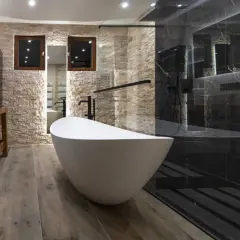 Salle de bain moderne avec baignoire îlot blanche et douche à l'italienne aux murs de marbre noir.