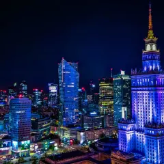 Nocna panorama Warszawy i okolic. Wieżowce rozświetlone neonami tworzą magiczny krajobraz.