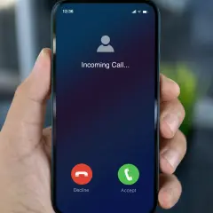 Dłoń trzyma smartfon z ekranem "Incoming Call...". Dowiedz się, jak dzwonić przez internet za darmo, by zawsze być w kontakcie.