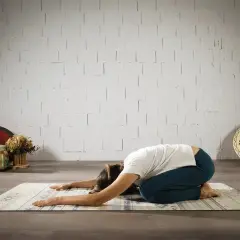 Mujer en postura de niño, buscando el yoga significado espiritual. Relajación y conexión interior.