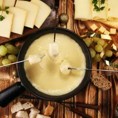 Fondue au fromage, une spécialité Auvergne Rhône Alpes, avec pain, raisins et tomates.