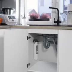 Pod zlewem widać, jak zamontować filtr do wody. Jest on podłączony do instalacji wodnej.