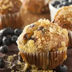 Frisch gebackene Blaubeermuffins mit Streuseln, ein köstliches Muffins Rezept, umgeben von frischen Blaubeeren.