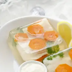 Dorsz w galarecie z marchewką i pietruszką, podany z cytryną i majonezem.