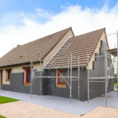 Maison en cours d'isolation par l'extérieur. Les inconvénients sont visibles : échafaudages, accès gêné, et aspect inachevé.
