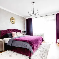 Elegancka sypialnia z łóżkiem w kolorze biskupi, aksamitnymi zasłonami i puszystym dywanem.